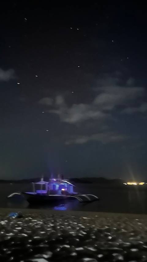       Very dark night sky photo with a few blurry light streaks and clouds.
  