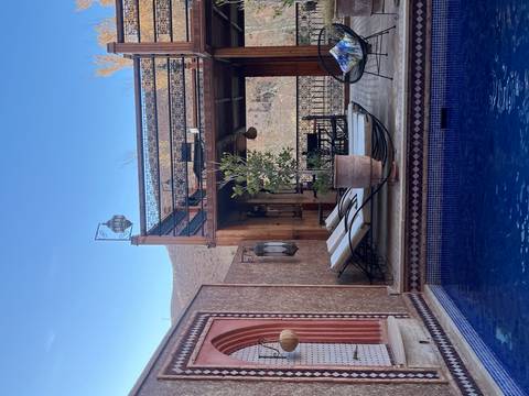       Boutique riad courtyard with loungers beside a tiled pool and mountain backdrop.
  