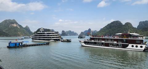       Tour boats and cruise ships anchored among karst islands in Ha Long Bay.
  