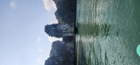       Tall limestone karst pillar rising from emerald waters in Ha Long Bay.
  