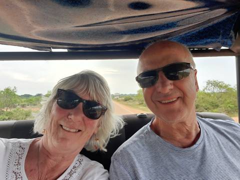       Close-up selfie of a couple wearing sunglasses during an open-top jeep ride.
  