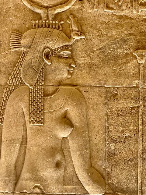       Close-up of finely detailed ancient Egyptian wall relief of a female figure.
  