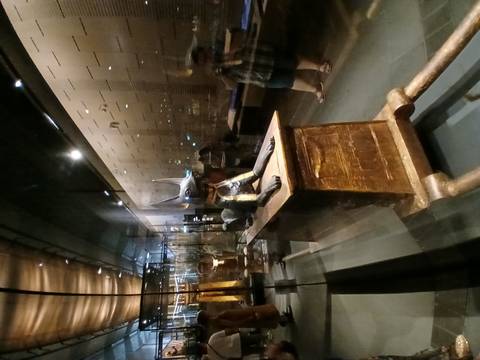       Indoor museum display of the black Anubis shrine behind reflective glass cases.
  