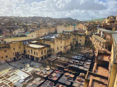       Panoramic view over the tannery pits and stacked ochre buildings of Fes Medina.
  