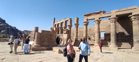       Tour group exploring the stone columns and ruins of Philae Temple on a sunny day.
  