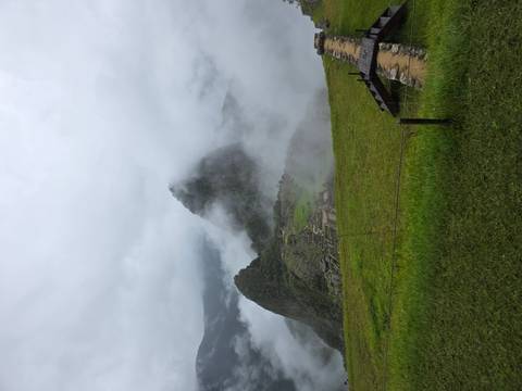       Machu Picchu citadel shrouded in mystical clouds rising above green terraces.
  