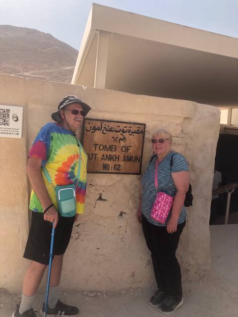       Two tourists posing beside the sign for Tutankhamun's tomb in the Valley of the Kings.
  