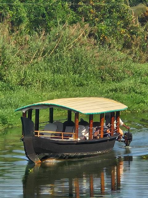       Traditional wooden houseboat gliding through lush green Kerala backwaters.
  