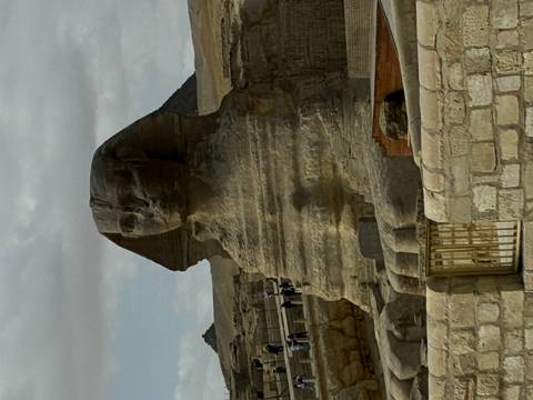       Close view of the weathered face of the Sphinx statue under a brooding sky.
  
