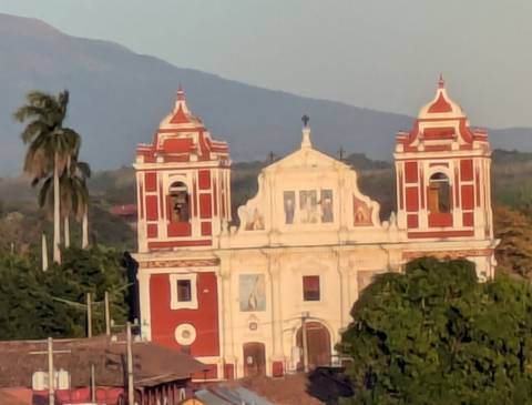       Zoomed image of a red and white colonial church with distant mountain backdrop.
  