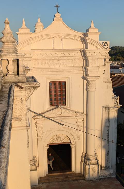       Architectural detail of León Cathedral rooftop showing ornate window and columns in warm evening sun.
  