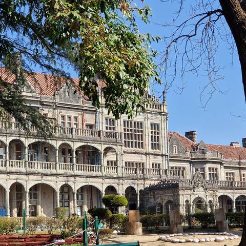       Historic colonial-era stone building with arched balconies and red-tile roof set against a clear blue sky.
  