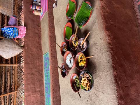       Traditional Sri Lankan meal served in clay bowls with rice, curries, and banana leaves on a rustic table.
  