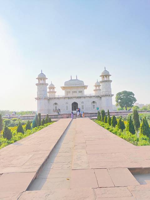       Visitors walk toward the ornate white Itimad-ud-Daulah tomb, known as the Baby Taj, on a bright day.
  