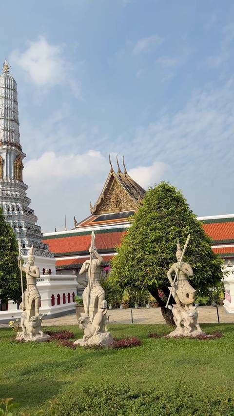       Ornate Thai temple roof with gilded naga finials and a manicured tree in the foreground.
  