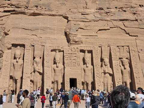       Detailed sandstone facade of Abu Simbel’s smaller temple with crowds of visitors below.
  
