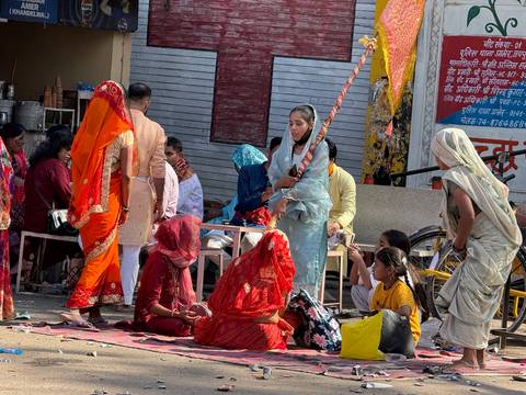       Street market scene with women in vivid saris engaged in animated conversation and trade.
  