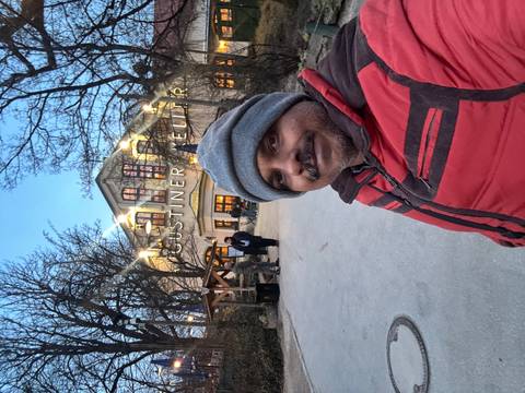       Selfie at dusk outside a lit Bavarian restaurant nestled among bare winter trees.
  
