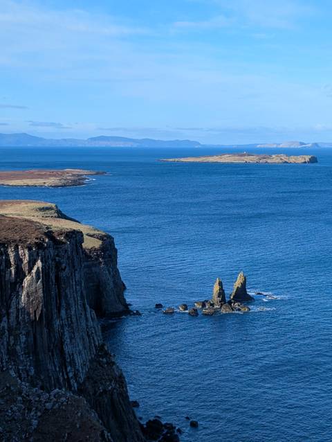       Rugged sea cliffs and offshore rock stacks under clear blue skies in the Scottish Highlands
  