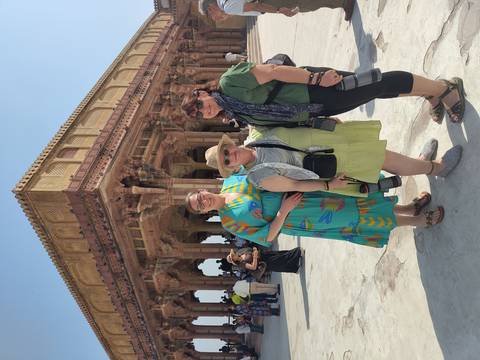       Travellers pose beneath the ornate pillared hall of a historic Indian fort complex.
  