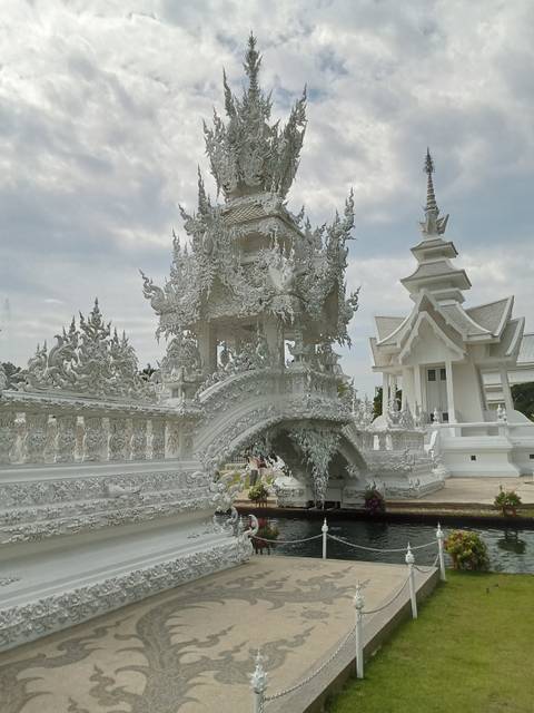       Ornate white temple structure with swirling stucco detail and tiered roofs set against a cloudy sky.
  