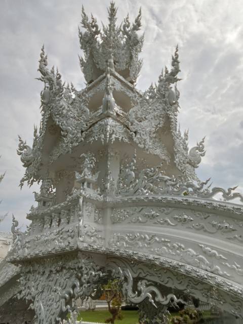      Close-up of intricate white stucco carvings and mythical creatures on the spire of the White Temple.
  