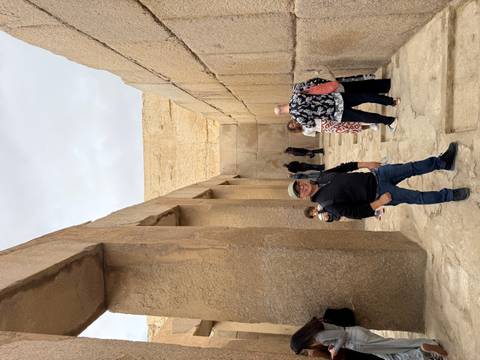       Tourists explore a narrow ancient stone corridor near the pyramids.
  