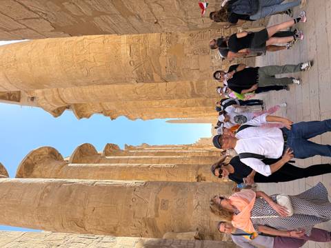       Crowd walks between massive hieroglyph-covered columns at Karnak Temple.
  