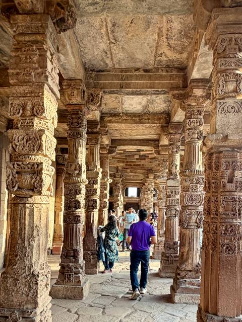       Elaborately carved sandstone columns and ceilings inside the Qutub complex crowded with visitors
  