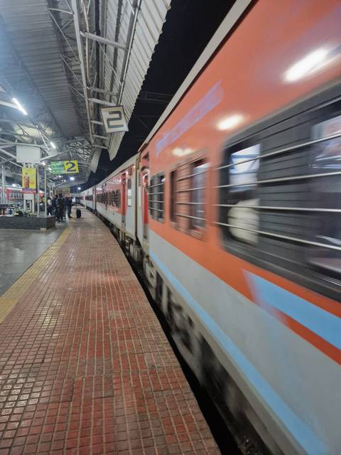       Blurred orange and white train pulling into covered station platform at night
  
