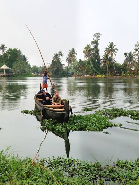       Small wooden canoe with tourists paddling through calm tropical backwaters
  