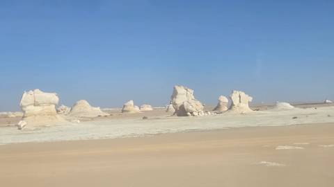       White chalk rock formations rising from flat desert in Egypt's White Desert
  