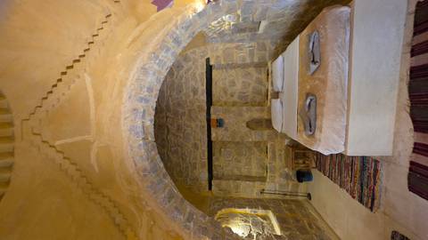       Cozy stone-arched desert lodge bedroom with warm lighting and rustic décor
  