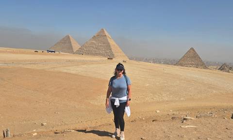       Traveller standing with the iconic Pyramids of Giza rising behind.
  