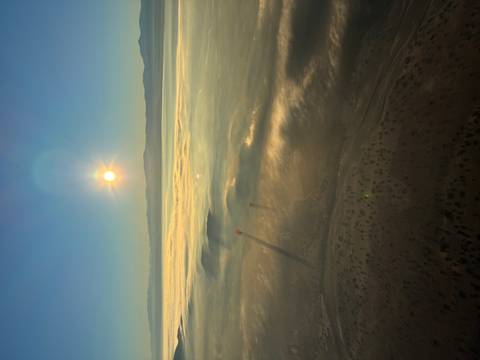       Sunrise above a blanket of mist with distant hot-air balloons casting long shadows.
  
