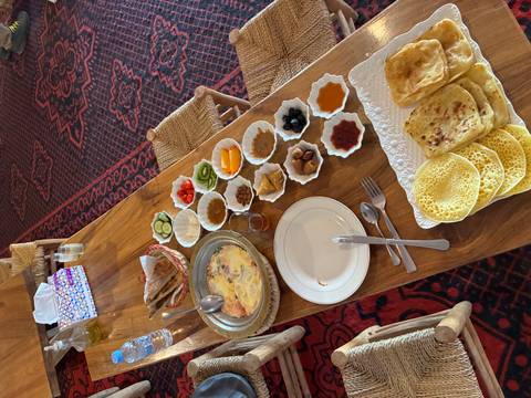      Traditional Moroccan breakfast spread with breads, jams and eggs on wooden table.
  