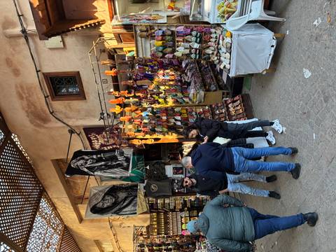      Bustling souk stall displaying colorful slippers and leather goods in Marrakech medina.
  