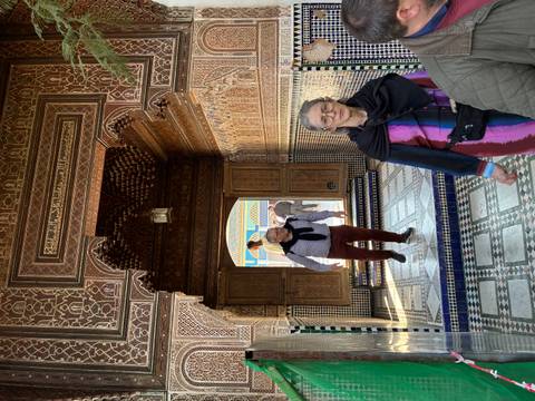       Visitors walking through ornate tiled archway of a Moroccan palace.
  