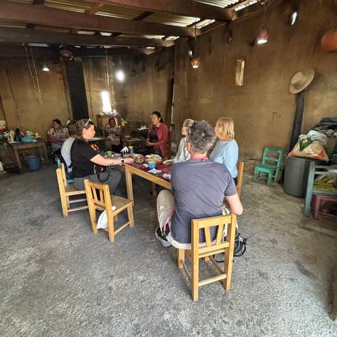       Travellers share a meal inside a rustic adobe home during a cultural visit.
  