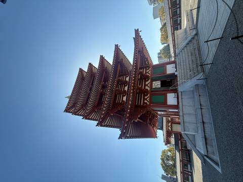       Traditional five-story wooden pagoda standing tall against a bright blue sky within a temple courtyard.
  