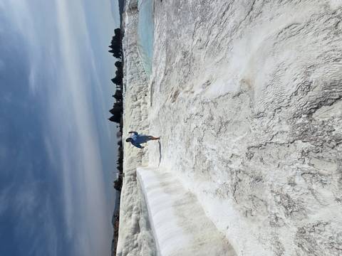      Person joyfully walks barefoot along the dazzling white travertine terraces of Pamukkale beside turquoise pools.
  