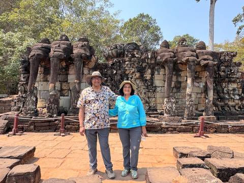       Couple posing in front of the Terrace of the Elephants with large elephant bas-relief statues.
  