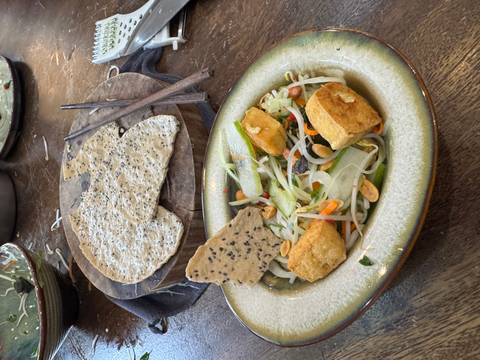       Close-up of Vietnamese salad with tofu and peanuts beside a sesame rice cracker and chopsticks.
  