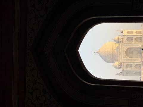       Taj Mahal framed perfectly within a dark Mughal archway at soft dawn light.
  