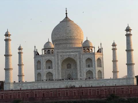       Close-up of the full Taj Mahal complex glowing in golden hour light with minarets towering.
  