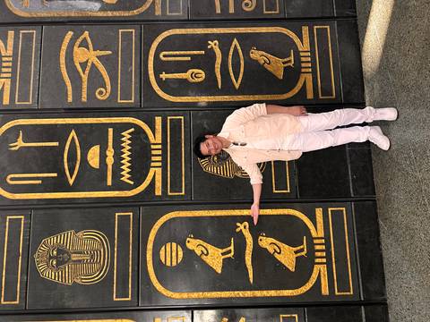       Visitor points to ornate black and gold doors decorated with ancient Egyptian symbols.
  