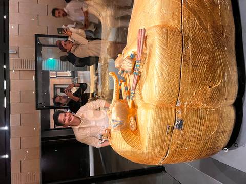       Golden sarcophagus exhibit viewed through glass while visitors capture photographs.
  