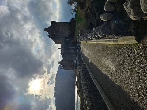       Moody view of Eilean Donan Castle at the end of a stone bridge under dramatic sky
  