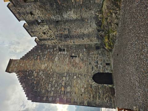       Close view of rugged stone castle walls and arched wooden doorway
  