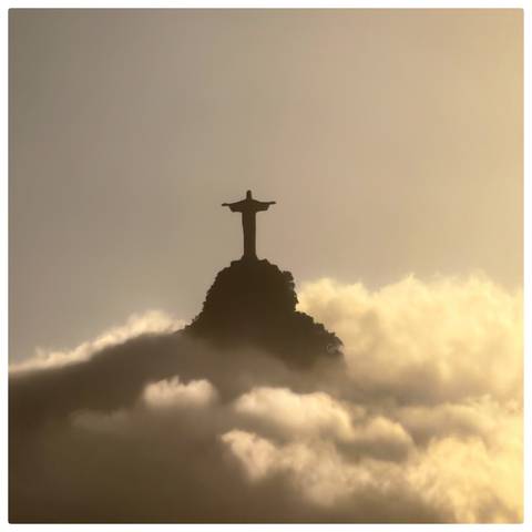       Christ the Redeemer statue silhouetted against golden clouds on a misty morning.
  